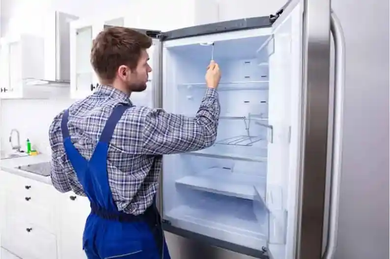 Skilled repair specialist servicing the inside of a refrigerator for efficient cooling and ice maker performance.